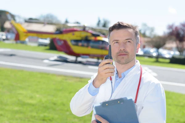 Médico em pé por um helicóptero com walkie-talkie — Fotografia de Stock