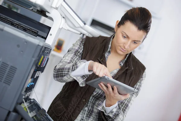 Frau repariert Drucker, während sie im Tablet nach Antworten sucht — Stockfoto