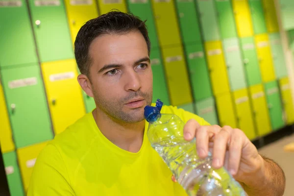 Beau homme buvant de l'eau dans les vestiaires — Photo