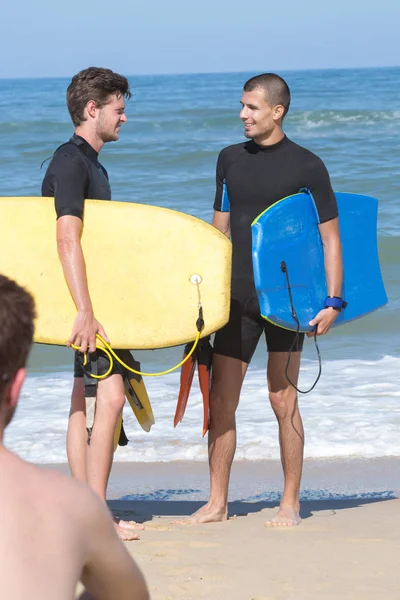 Jeunes hommes portent des bodyboards sur le rivage — Photo