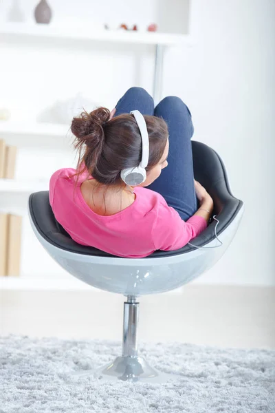 Woman listening to music in swivel chair — Stock Photo, Image