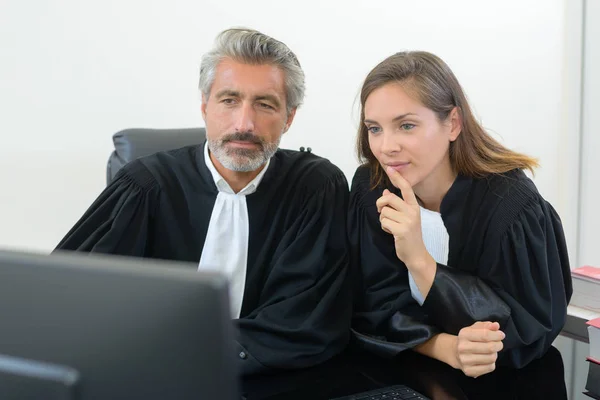 Male and female magistrates looking at computer — Stock Photo, Image