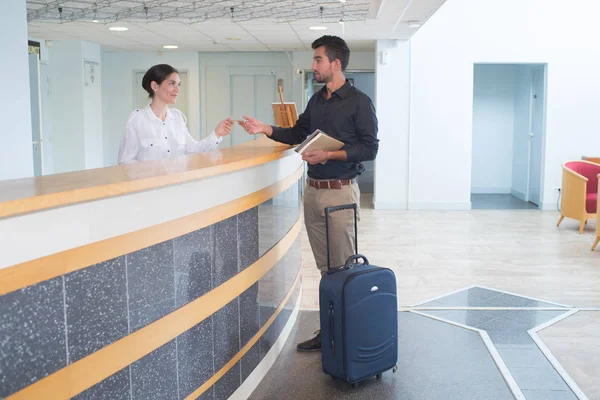 Friendly handsome hotel receptionist helping a male client — Stock Photo, Image
