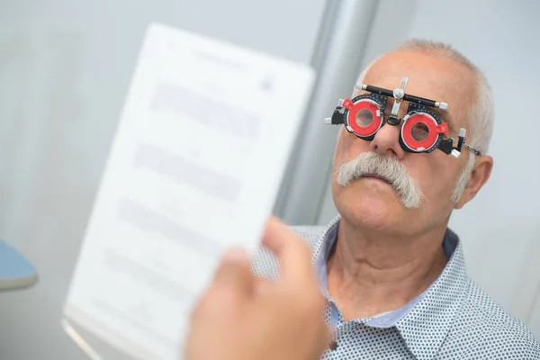 Óptico na cirurgia dando teste de olho homem — Fotografia de Stock