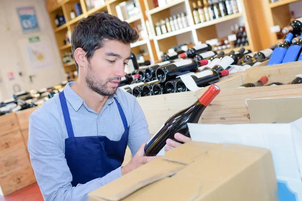 Joven sommelier leyendo la etiqueta de la bebida en el sótano —  Fotos de Stock