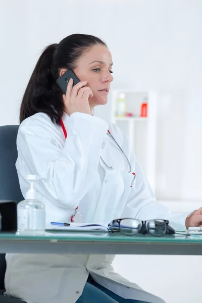Porträtt av kvinnliga läkare ringa på consulting room — Stockfoto
