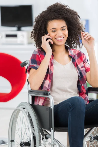 Mulher deficiente em cadeira de rodas usando telefone celular em casa — Fotografia de Stock