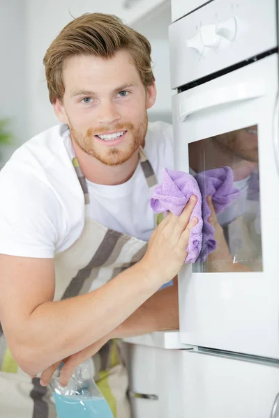 Junger Mann putzt Ofen — Stockfoto