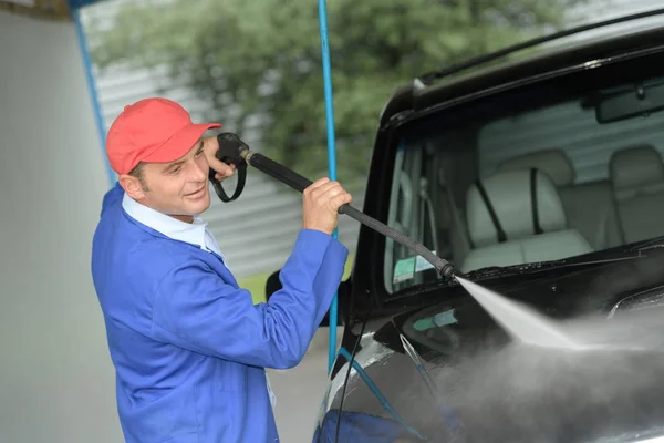 Hombre maduro lavando un coche con agua a presión — Foto de Stock