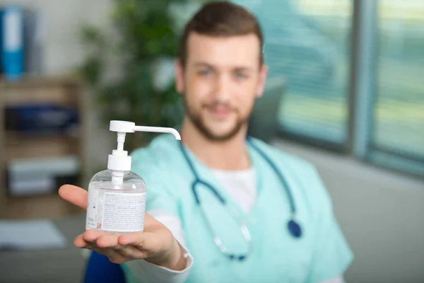 Medico che mostra un flacone pompa gel mano — Foto Stock