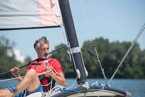 Junger Mann steht auf der Jacht im Meer — Stockfoto