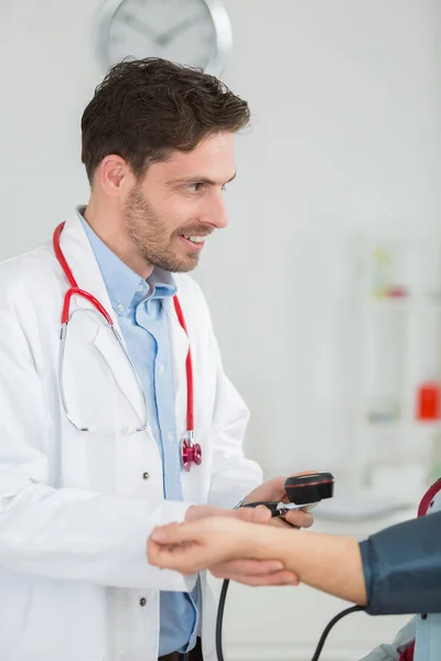 Retrato del médico feliz revisando la presión arterial de los pacientes en la clínica — Foto de Stock