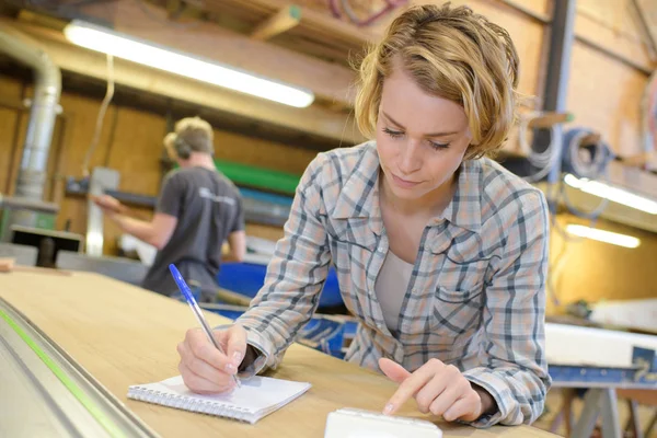 Ung kvinna byggnadsarbetare skriva på anteckningsboken — Stockfoto