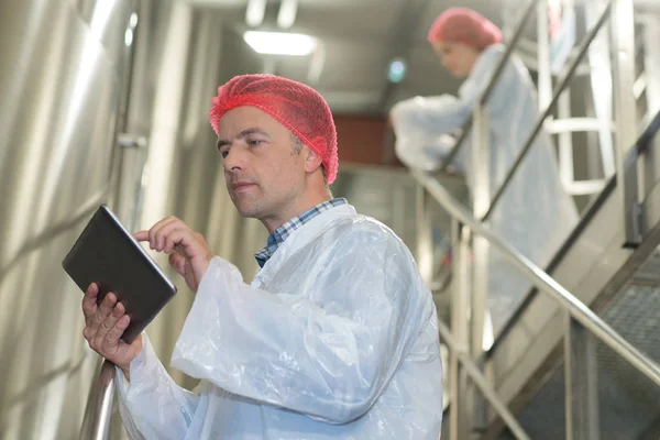 Hombre mirando la tableta mientras trabaja en la fábrica de embotellado — Foto de Stock