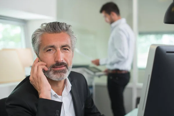 Uomo d'affari esperto al telefono sul posto di lavoro — Foto Stock