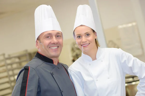 Portret van gastvrije chef-kok en zijn helper in restaurant — Stockfoto