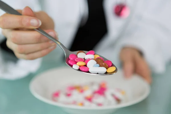 Pills in spoon on white dish — Stock Photo, Image