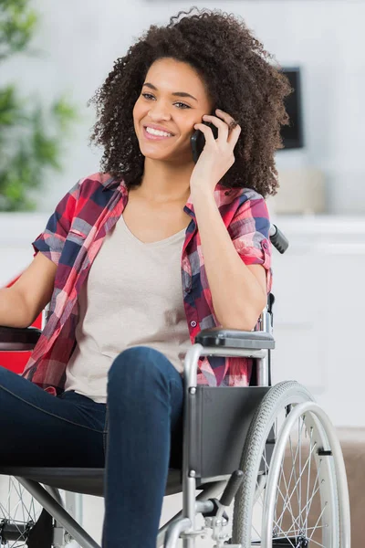 Ung kvinna i rullstol med mobiltelefon — Stockfoto