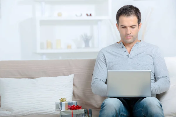 Mann mit Geschenken und Laptop — Stockfoto