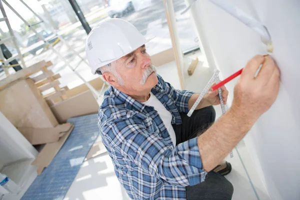 Volwassen man die de muur markeren met een potlood — Stockfoto