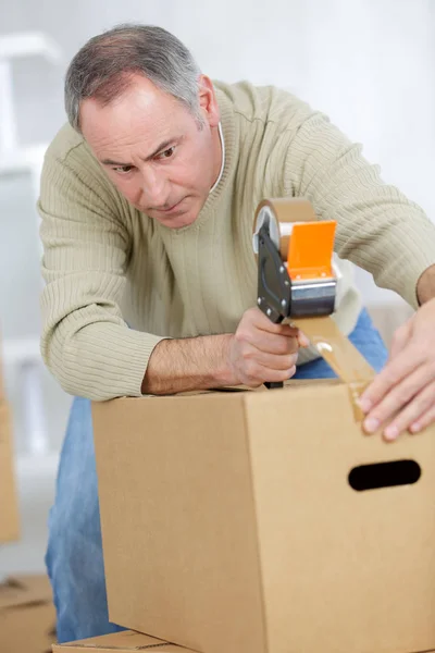 Muž těsnící lepenkové krabice s hnědou páskou — Stock fotografie