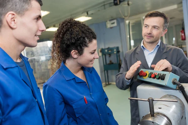 Mann zeigt zwei Auszubildenden Steuerung der Maschine — Stockfoto