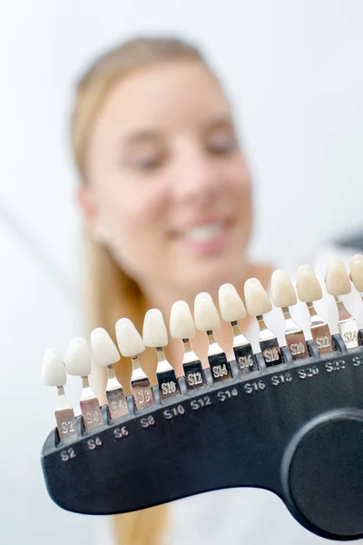 Señora sonriendo detrás de la fila de dientes falsos —  Fotos de Stock