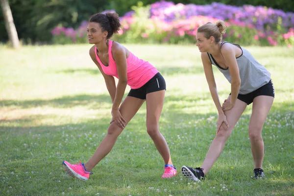 Två vänner sträcker benmusklerna efter träning — Stockfoto