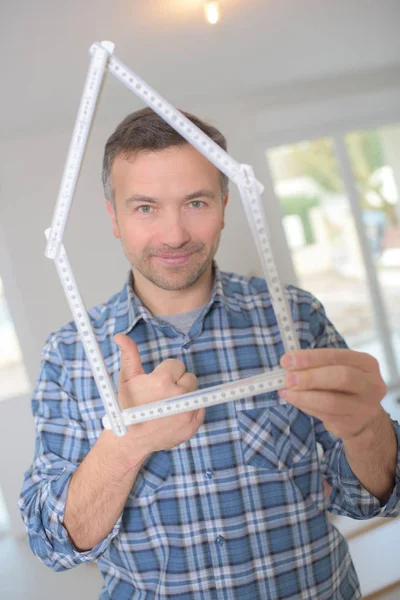 Glücklicher Mann mit einem Maßstab in Form eines Hauses — Stockfoto