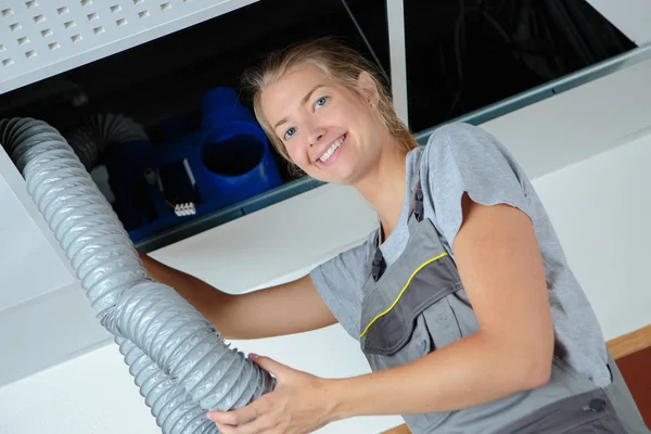 Mujer en una escalera que trabaja con tubos de ventilación —  Fotos de Stock