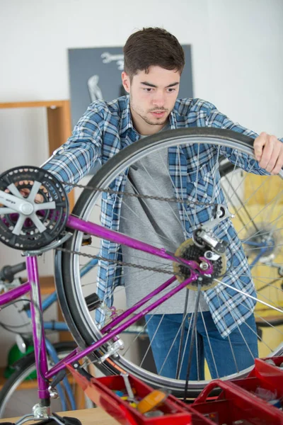 Manitas fijando rueda de bicicleta en su garaje — Foto de Stock