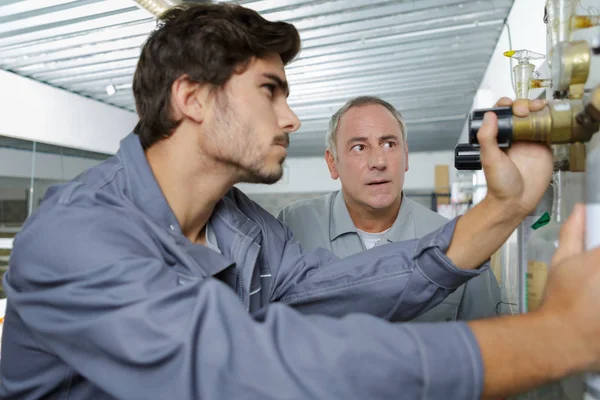 Giovani e un vecchio tecnico durante il loro lavoro — Foto Stock