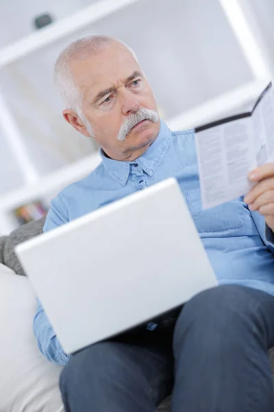 Senior man op de bank met laptop computer — Stockfoto