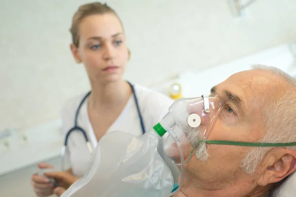 Close-up of senior man using oxygen mask in clinic — Stock Photo, Image