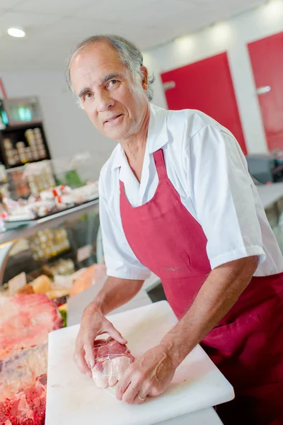 Slaktaren poserar med en bit kött — Stockfoto