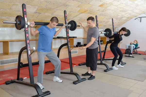 Tonårsträning med vikter på gym klubb med tränare — Stockfoto