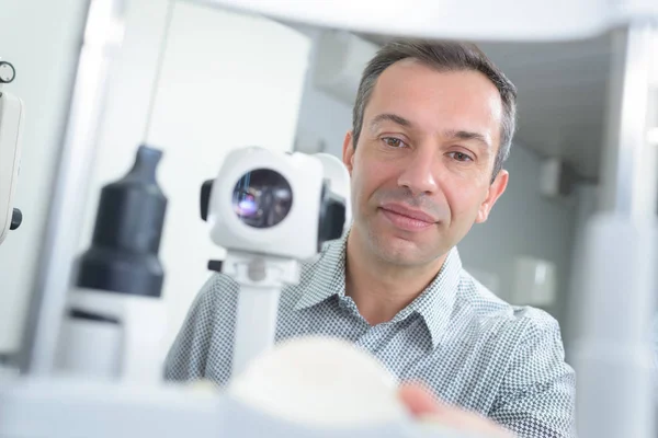 Optometrista com tonômetro sem contato verificando a pressão intraocular do paciente — Fotografia de Stock