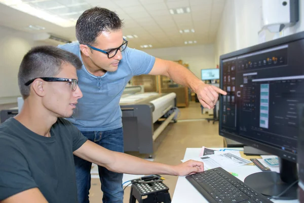 Двое мужчин в очках смотрят на экран компьютера — стоковое фото
