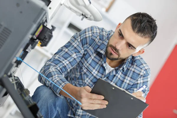 Hombre técnico reparación de una impresora en el lugar de negocios en el trabajo —  Fotos de Stock