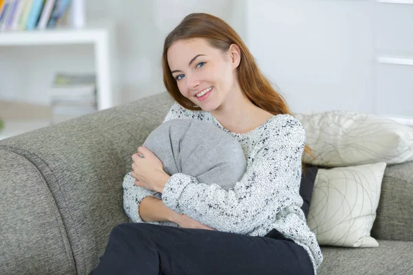 В полный рост молодая женщина держит подушку на диване — стоковое фото