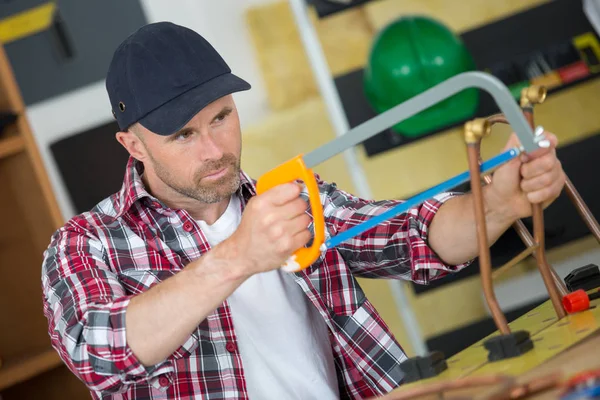 Männer zerschneiden Metallrohr mit Handsäge — Stockfoto