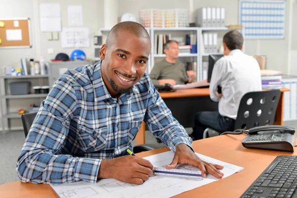 Office worker sat writing at his desk — Stock Photo, Image