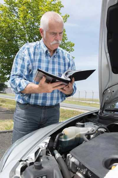 Older man checking levels and servicing his car — Stock Photo, Image