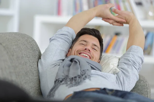 Man stretching on his couch — Stock Photo, Image