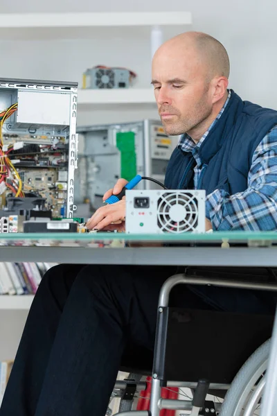 Mann im Rollstuhl repariert Computer — Stockfoto