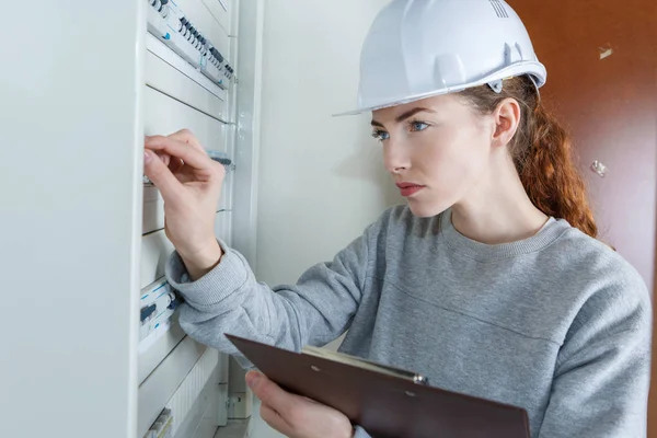 Kvinnlig arbetstagare att trycka spaken i säkringsdosan — Stockfoto