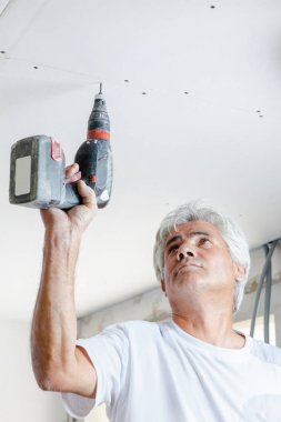 Man screwing plasterboard to ceiling clipart