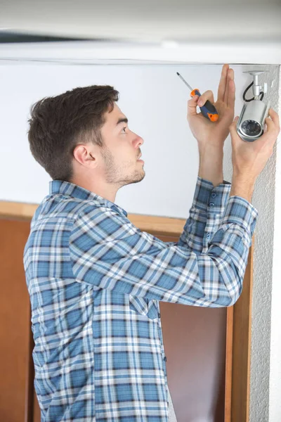 Young man fitting security camera