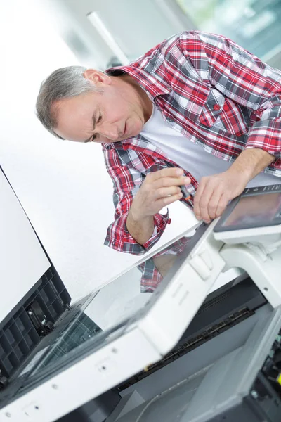 Homem usando chave de fenda na fotocopiadora — Fotografia de Stock