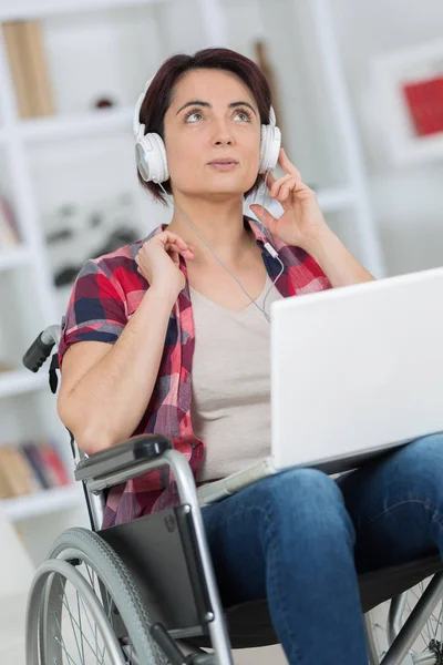 Vrouw in een rolstoel geniet van muziek in hoofdtelefoons — Stockfoto